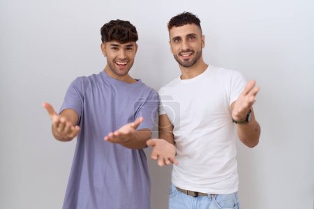 Photo pour Homosexuel gay couple debout sur blanc fond sourire joyeux offrant mains donnant assistance et acceptation. - image libre de droit