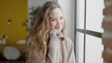 Téléchargez les photos : Jeune belle femme hispanique souriant confiant regarder jeter la fenêtre à la maison - en image libre de droit