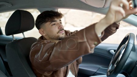 Foto de Hombre árabe joven tocando la vista trasera sentado en el coche en la calle - Imagen libre de derechos