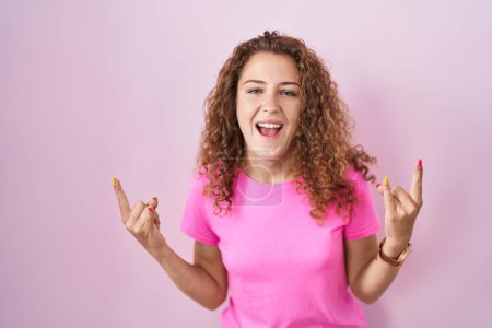 Photo for Young caucasian woman standing over pink background shouting with crazy expression doing rock symbol with hands up. music star. heavy music concept. - Royalty Free Image