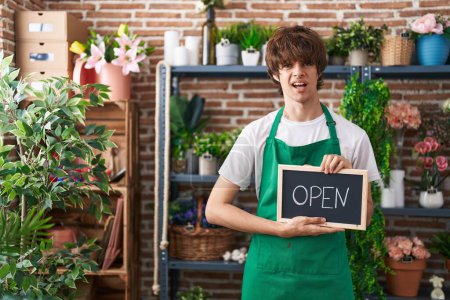 Photo for Hispanic young man working at florist holding open sign clueless and confused expression. doubt concept. - Royalty Free Image