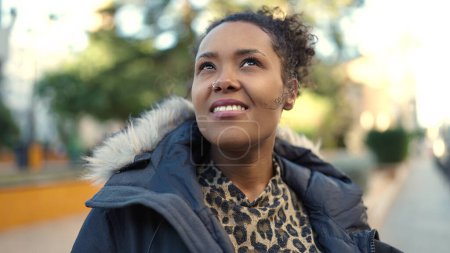 Téléchargez les photos : Afro-américaine femme souriant confiant regardant vers le ciel au parc - en image libre de droit