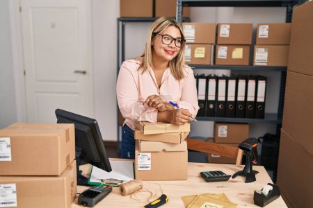 Téléchargez les photos : Jeune femme hispanique e-commerce travailleur d'affaires s'appuyant sur des paquets au bureau - en image libre de droit
