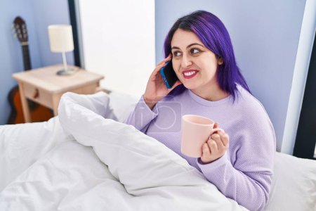 Photo for Young beautiful plus size woman talking on smartphone drinking coffee at bedroom - Royalty Free Image