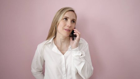 Photo for Young blonde woman talking on smartphone standing over isolated pink background - Royalty Free Image