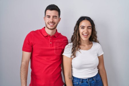 Téléchargez les photos : Jeune couple hispanique debout sur fond isolé clin d'oeil en regardant la caméra avec une expression sexy, gai et heureux visage. - en image libre de droit