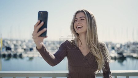 Foto de Mujer rubia joven sonriendo confiado haciendo selfie por el teléfono inteligente en la playa - Imagen libre de derechos