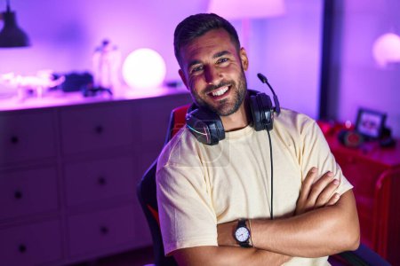 Photo for Young hispanic man streamer smiling confident sitting with arms crossed gesture at gaming room - Royalty Free Image