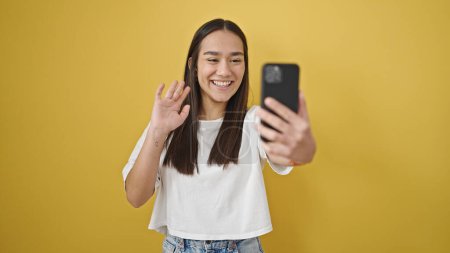 Téléchargez les photos : Jeune belle femme hispanique souriant ayant appel vidéo sur fond jaune isolé - en image libre de droit