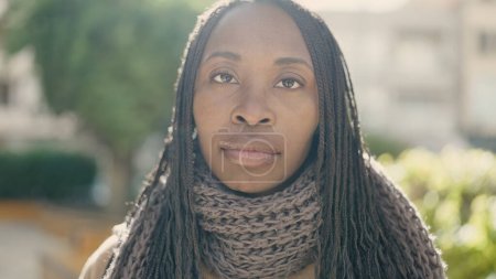 Téléchargez les photos : Femme africaine debout avec une expression sérieuse au parc - en image libre de droit