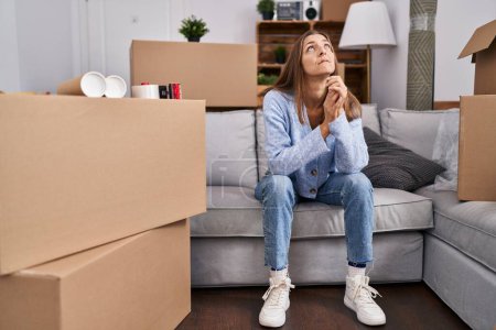 Photo for Young woman with worried expression sitting on sofa at new home - Royalty Free Image
