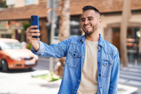 Téléchargez les photos : Young hispanic man smiling confident making selfie by the smartphone at street - en image libre de droit