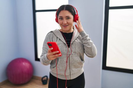 Photo for Young hispanic woman smiling confident listening to music training at sport center - Royalty Free Image