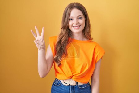 Photo for Caucasian woman standing over yellow background showing and pointing up with fingers number three while smiling confident and happy. - Royalty Free Image