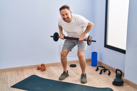 Photo for Young caucasian man smiling confident using bar and weight disc at sport center - Royalty Free Image