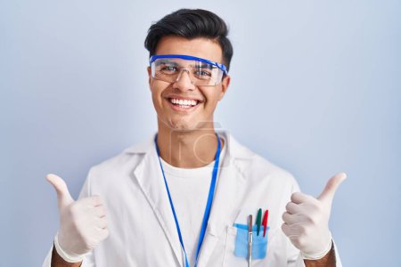 Photo for Hispanic man working as scientist success sign doing positive gesture with hand, thumbs up smiling and happy. cheerful expression and winner gesture. - Royalty Free Image