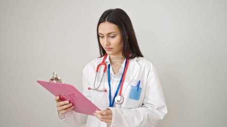 Foto de Joven hermosa mujer hispana médico leyendo informe médico sobre fondo blanco aislado - Imagen libre de derechos