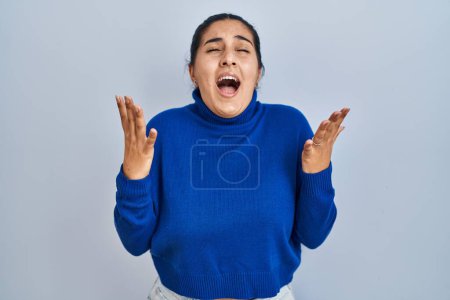 Téléchargez les photos : Jeune femme hispanique debout sur fond isolé célébrant fou et fou de succès avec les bras levés et les yeux fermés hurlant excité. concept gagnant - en image libre de droit