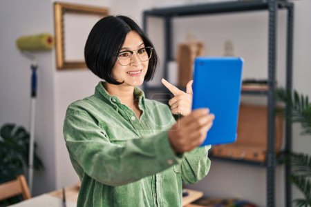Téléchargez les photos : Jeune femme asiatique faire appel vidéo avec tablette souriant heureux pointage avec la main et le doigt - en image libre de droit