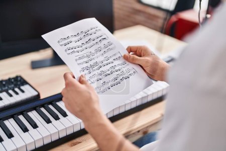 Téléchargez les photos : Jeune homme arabe musicien lisant une partition musicale au studio de musique - en image libre de droit