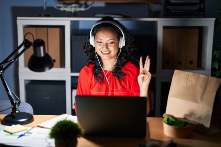 Photo for Young asian woman working at the office with laptop at night showing and pointing up with fingers number three while smiling confident and happy. - Royalty Free Image