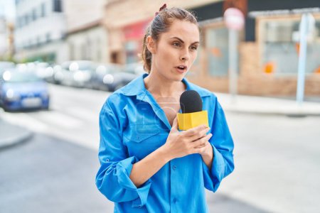 Téléchargez les photos : Jeune femme journaliste travaillant au microphone dans la rue - en image libre de droit