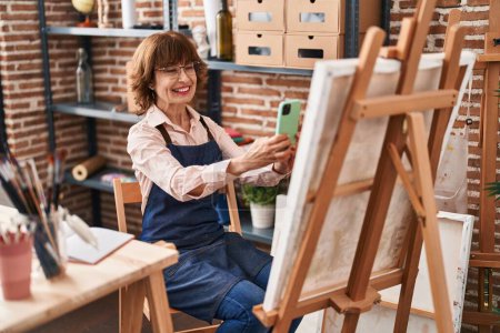 Téléchargez les photos : Femme artiste du Moyen Âge faire une photo pour dessiner par smartphone au studio d'art - en image libre de droit