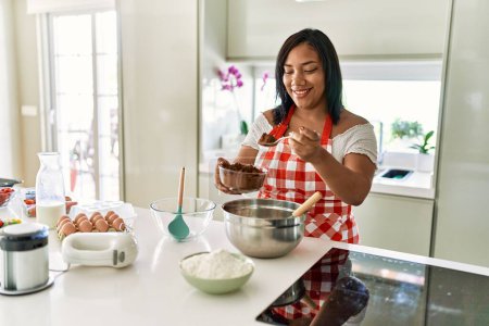 Photo for Hispanic brunette woman preparing chocolate cake at the kitchen - Royalty Free Image