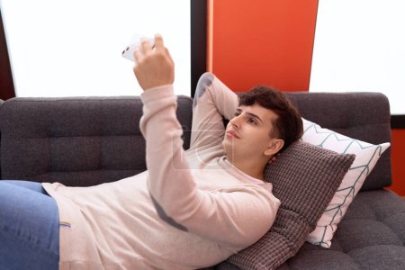 Photo for Non binary man make selfie by smartphone lying on sofa at home - Royalty Free Image