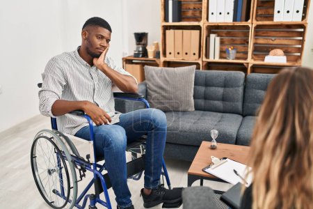 Téléchargez les photos : Afro-Américain faisant de la thérapie assis sur fauteuil roulant pensant fatigué et ennuyé avec des problèmes de dépression avec les bras croisés. - en image libre de droit