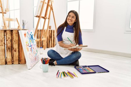 Photo for Young latin woman smiling confident drawing on notebook at art studio - Royalty Free Image