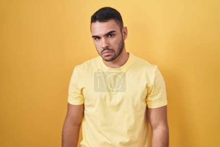 Téléchargez les photos : Young hispanic man standing over yellow background depressed and worry for distress, crying angry and afraid. sad expression. - en image libre de droit