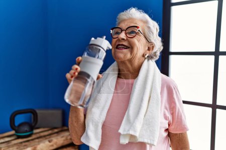 Photo for Senior grey-haired woman wearing sportswear holding water bottle at sport center - Royalty Free Image