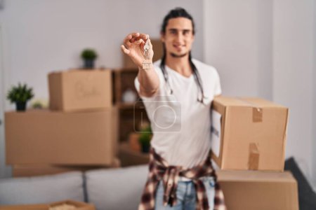 Photo for Young man holding package and key at new home - Royalty Free Image