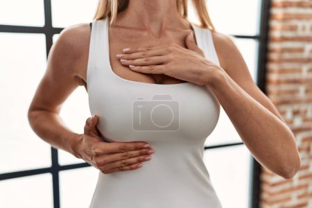 Téléchargez les photos : Young blonde woman examining breast at home - en image libre de droit