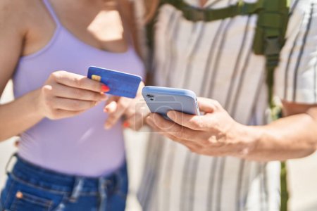 Foto de Hombre y mujer pareja turística utilizando smartphone y tarjeta de crédito en la calle - Imagen libre de derechos