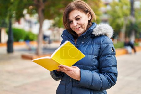 Photo for Middle age woman smiling confident reading book at park - Royalty Free Image