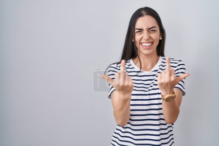 Foto de Young brunette woman wearing striped t shirt showing middle finger doing fuck you bad expression, provocation and rude attitude. screaming excited - Imagen libre de derechos