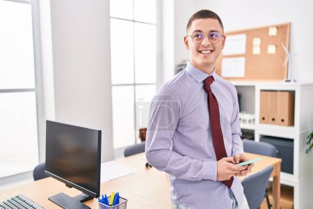 Photo for Young hispanic man business worker smiling confident using smartphone at office - Royalty Free Image