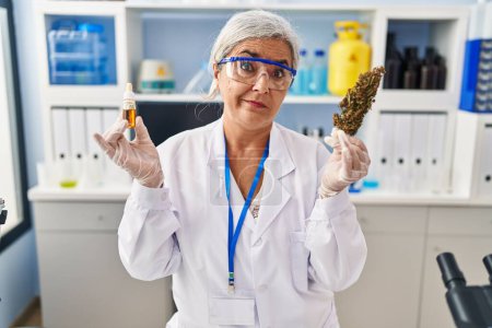 Photo for Middle age woman with grey hair doing weed oil extraction at laboratory skeptic and nervous, frowning upset because of problem. negative person. - Royalty Free Image