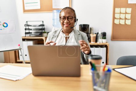 Foto de Mujer afroamericana mayor agente de centro de llamadas que tiene videollamada en la oficina - Imagen libre de derechos