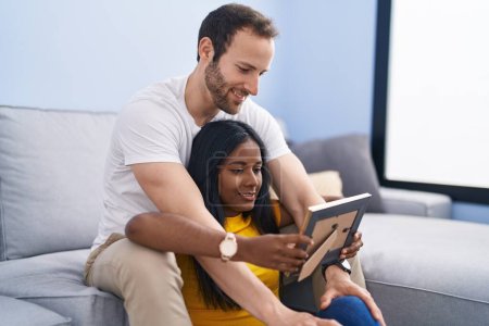 Téléchargez les photos : Man and woman interracial couple looking picture at home - en image libre de droit