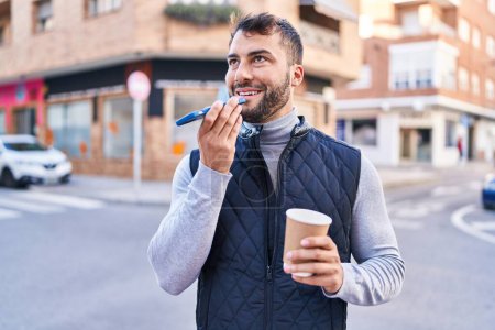 Foto de Joven hispano hablando en el smartphone tomando café en la calle - Imagen libre de derechos