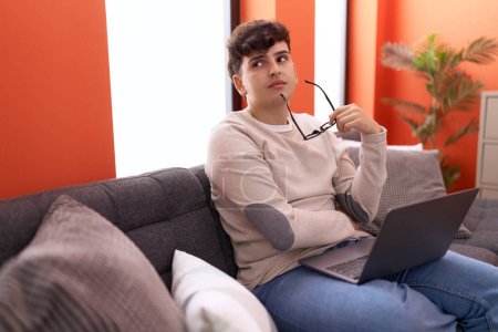 Photo for Non binary man using laptop with worried expression at home - Royalty Free Image