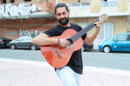 Photo for Young hispanic man musician playing classical guitar at street - Royalty Free Image