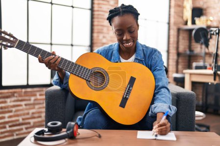Foto de Mujer afroamericana músico componiendo canción tocando guitarra clásica en estudio de música - Imagen libre de derechos