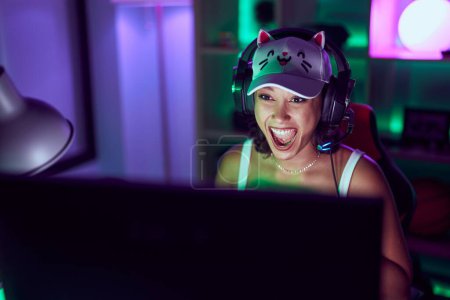 Téléchargez les photos : Young beautiful hispanic woman streamer playing video game using computer at gaming room - en image libre de droit