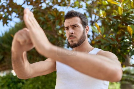 Photo for Young hispanic man karate fighter doing combat salute at park - Royalty Free Image