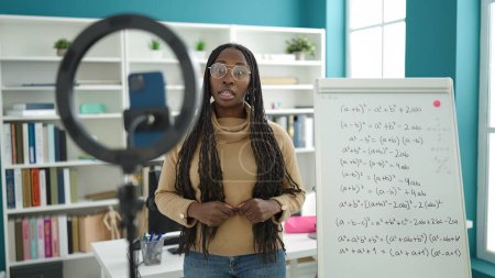 Photo for African woman recording teaching maths on magnetic board at library university - Royalty Free Image