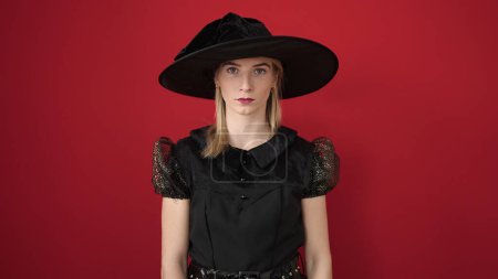 Téléchargez les photos : Jeune femme blonde portant un costume de sorcière sur fond rouge isolé - en image libre de droit